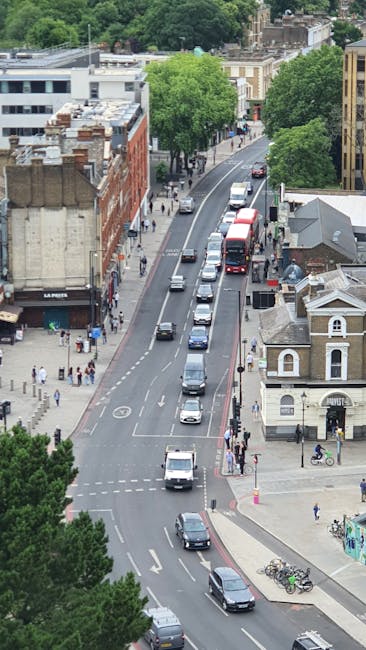 A busy street scene on Streatham High Road featuring a line of parked cars and a double-decker bus in motion, with a row of brick and white-painted terraced shops and residential buildings along the p